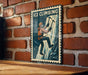 A vintage-style metal sign with a climbing figure on it, mounted on a brick wall.