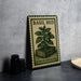 A metal sign with a basil plant illustration and text, placed on a table next to some black containers.