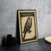 A framed illustration of a parakeet, a small parrot, is displayed on a table next to some black camera lenses.