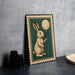 A framed illustration of a rabbit holding a balloon is displayed on a table.