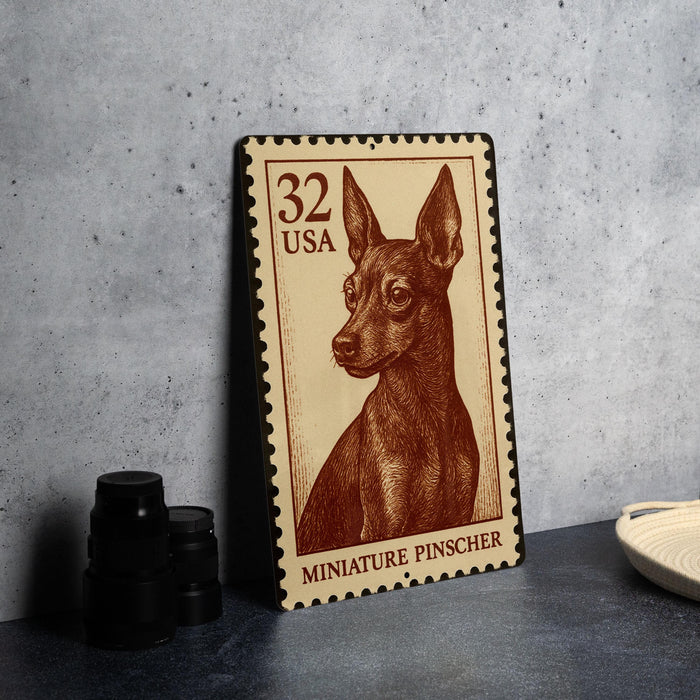 A metal stamp featuring a miniature pinscher dog, with the text "32 USA" and "MINIATURE PINSCHER" printed on it.