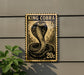 A King Cobra postage stamp is displayed on a wall, with a plant visible to the left.