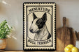 a bull terrier, a small dog breed, with a sign that reads "Miniature Bull Terrier" in the center. The sign is placed on a shelf next to a wooden cutting board and a potted plant.