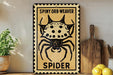 a sign with a spider illustration, placed on a wooden surface next to a wooden cutting board and some lemons.