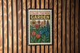 A colorful garden-themed sign is displayed on a wooden wall.