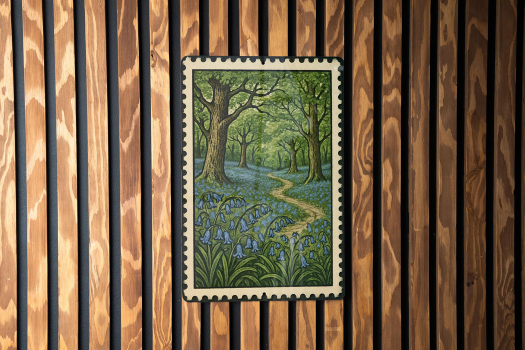 A framed painting depicting a lush forest scene with a winding path through the trees and blue flowers.