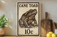 a sign with a drawing of a cane toad, placed on a wooden surface next to a potted plant and a wooden cutting board.