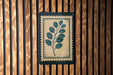 a wooden wall with a framed print of a leafy plant on it.