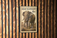 a large Asian elephant stamp mounted on a wooden wall.
