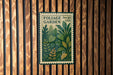 a vintage-style postage stamp with a lush green plant illustration, mounted on a wooden wall.