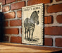 A framed illustration of a zebra is displayed on a brick wall, with the text "GREVY'S ZEBRA" printed on the frame.