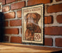 A French Mastiff dog is depicted on a postage stamp-like frame, mounted on a brick wall.