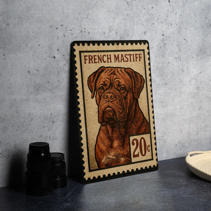A French mastiff dog is depicted on a postage stamp-like frame, placed on a countertop next to some black camera lenses.