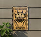 a sign with a spider on it, mounted on a wall.