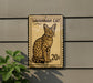 A Savannah cat postage stamp is displayed on a wall, with a plant to the left.