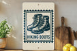 A sign with the text "HIKING BOOTS" and an illustration of hiking boots, placed on a wooden surface next to a wooden cutting board and some lemons.