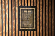 a framed artwork with a floral design, mounted on a wooden wall.