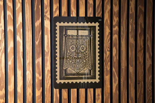 a framed artwork with a floral design, mounted on a wooden wall.