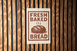 A sign that reads "FRESH BAKED BREAD" with an illustration of a loaf of bread.