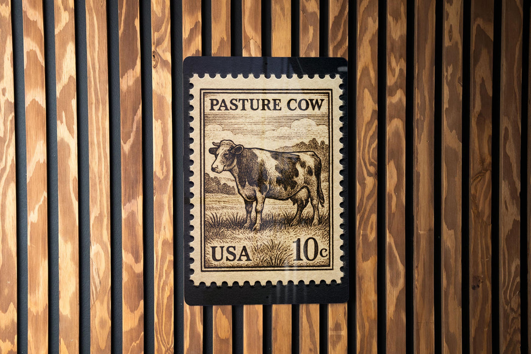 A postage stamp featuring a cow is displayed on a wooden wall.