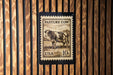 A postage stamp featuring a cow is displayed on a wooden wall.