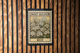 a framed print of a flower with the text "Sweet Alyssum Bed" on it, hanging on a wooden wall.