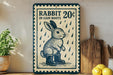 A vintage-style sign advertising "Rabbit 20¢ in Rain Boots" is displayed on a wooden shelf, accompanied by a potted plant and a wooden cutting board.