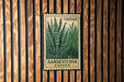 a metal sign with a plant illustration, mounted on a wooden wall.