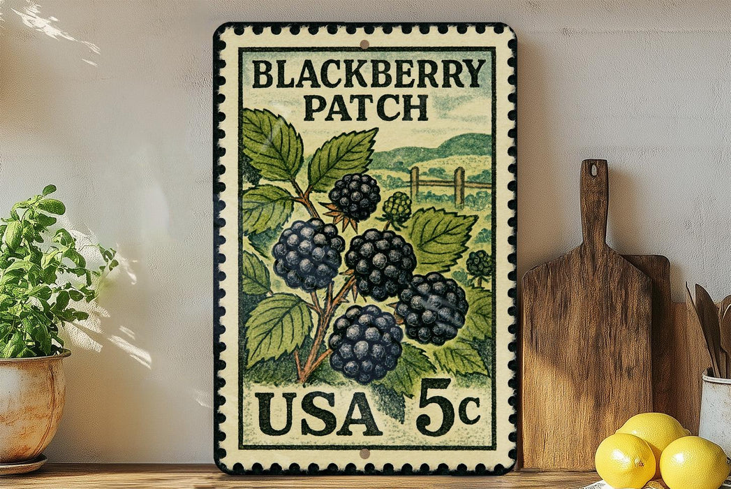 A vintage-style stamp depicting a blackberry patch, with the text "BLACKBERRY PATCH" and "USA 5c" printed on it. The stamp is placed on a wooden surface, with a potted plant, a wooden cutting board, and some lemons nearby.