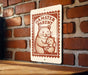 A sign with a hamster and a baby hamster, mounted on a brick wall.