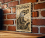 a wooden plaque with a black and white illustration of a crocodile, mounted on a brick wall.