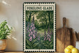 a framed illustration of pink bell-shaped flowers, with the text "FOXGLOVE GLADE" above the illustration. The frame is placed on a wooden surface, with a potted plant to the left and a wooden cutting board to the right.