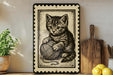 a framed illustration of a kitten sitting on a ball of yarn, surrounded by various kitchen utensils and a potted plant.