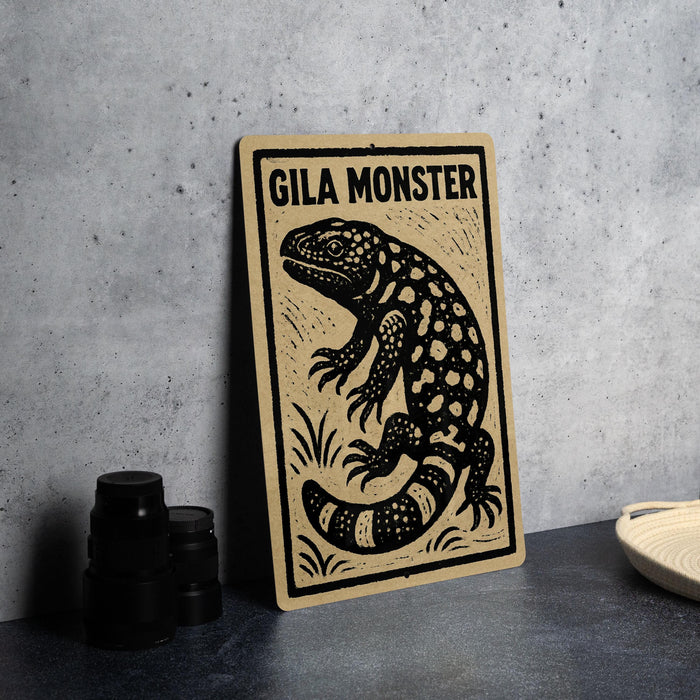 a wooden sign with a black and white illustration of a gila monster, a type of lizard, on a beige background.