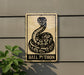 a sign with a snake and the text "BALL PYTHON" on it, mounted on a wall next to a plant.