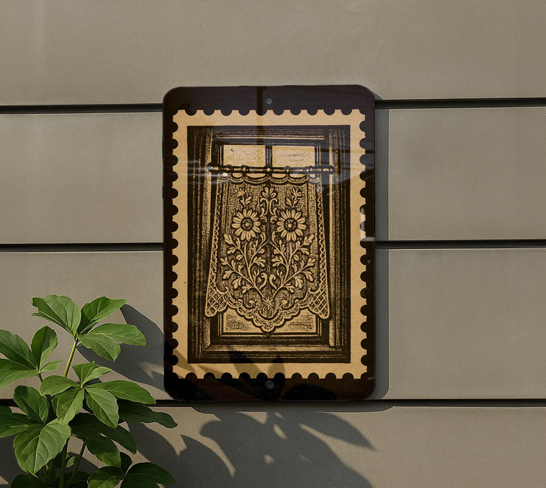 a framed picture of a floral design on a wall, with a plant to the left of the frame.