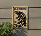 a sign with a black and white illustration of a lizard or salamander, mounted on a wall.
