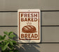 a sign that reads "Fresh Baked Bread" with a picture of a loaf of bread on it.