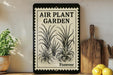 a vintage-style sign that reads "Air Plant Garden Forever" with illustrations of plants on it, placed on a shelf next to a wooden cutting board and some potted plants.