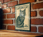A metal sign with a cat illustration and the text "LAPERM CAT 44c" is displayed on a brick wall.