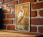 a large, detailed illustration of a heron standing on a brick wall.