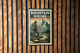 A vintage-style metal sign with a hiker standing in front of a mountain landscape, mounted on a wooden wall.