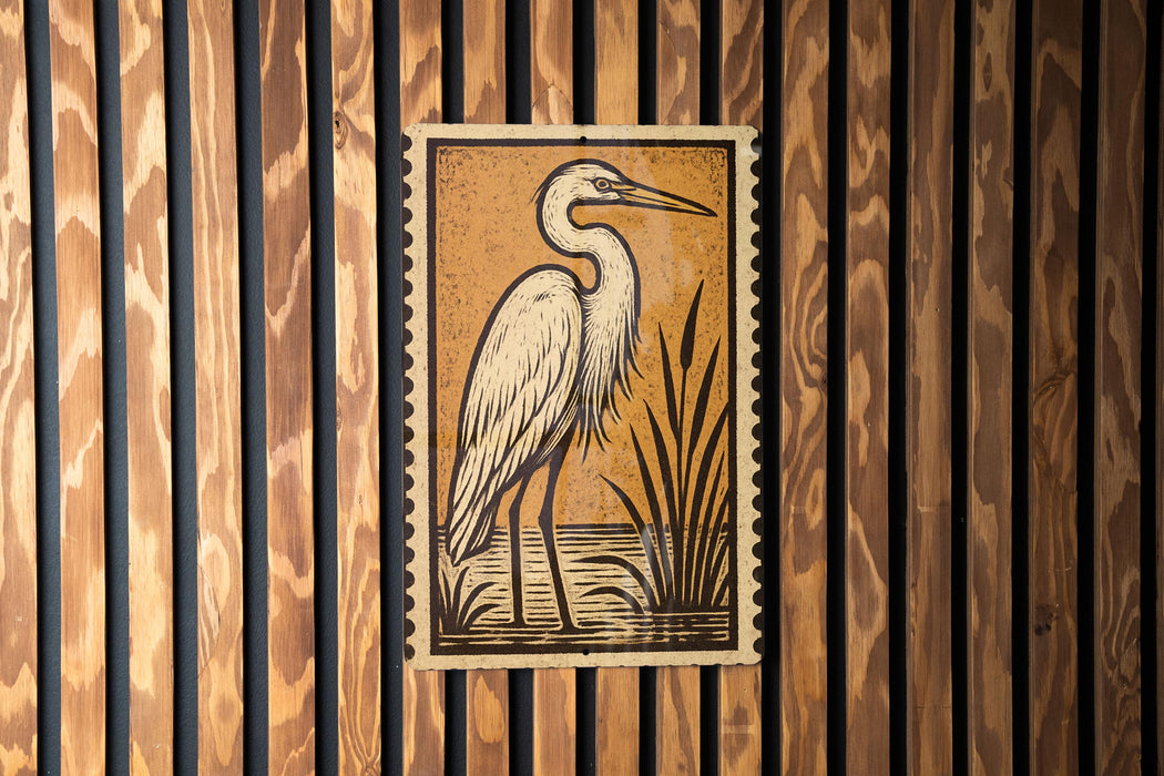 a large, white heron standing in a grassy area, with a wooden fence in the background.