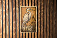 a large, white heron standing in a grassy area, with a wooden fence in the background.