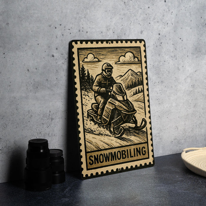 A metal sign featuring a snowmobile rider, with the word "Snowmobiling" written below the illustration.
