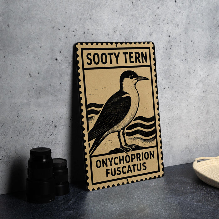 A metal sign with a bird illustration and text, placed on a table next to some black camera lenses.