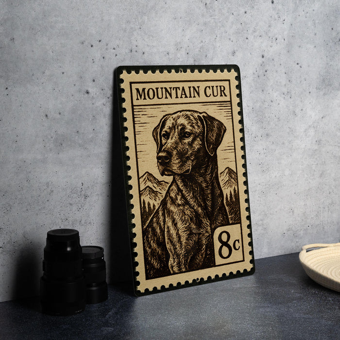 A metal stamp featuring a dog on a mountain landscape, with the text "MOUNTAIN CUR" and the denomination "8c".