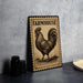 a wooden sign with a rooster illustration, placed on a table next to some black containers.