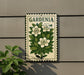 A sign with the word "GARDENIA" and a floral illustration of white flowers and green leaves is displayed on a wall.
