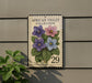 a decorative stamp-like sign with a floral design, mounted on a wall next to a plant.